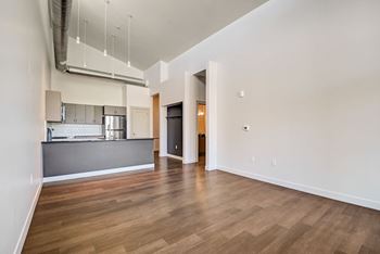 a bedroom with a medium sized bed and a kitchen in the background